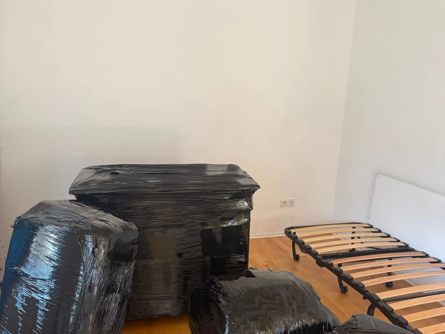 In Folie gewickelte Polstermöbel und ein zerlegtes Bett in einem leergeräumten Zimmer